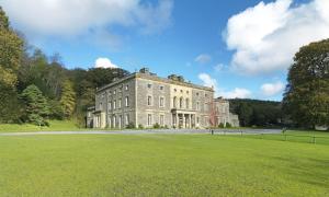 a large brick building with a grass field in front at Plas Nanteos Mansion in Aberystwyth