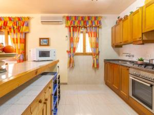 cocina con armarios de madera y microondas en Holiday Home Fumadell by Interhome, en Riumar