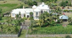 a large white house on a hill with palm trees at Le Refuge in Rodrigues Island