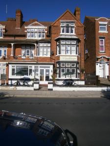 a large brick building with white windows on a street at Woodthorpe Hotel in Skegness