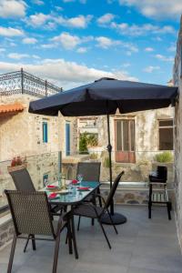 Marilena Natural Stone House في Pigi: طاولة وكراسي مع مظلة على الفناء