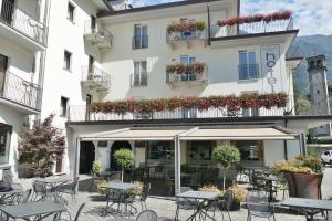 ein Hotel mit Tischen und Stühlen vor einem Gebäude in der Unterkunft Hotel San Lorenzo Chiavenna in Chiavenna