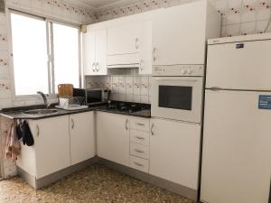 a kitchen with white cabinets and a white refrigerator at 250 Playa in Puerto de Sagunto