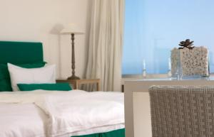 a bedroom with a bed and a chair and a window at Relais Blu in Massa Lubrense
