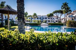 a view of a resort pool with palm trees and buildings at Apartamentos Coto de San José in Chiclana de la Frontera