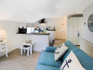 a living room with a blue couch and a kitchen at Amolca in Amlwch