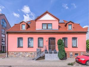 ein rosafarbenes Haus mit orangefarbenem Dach in der Unterkunft Ferienhaus Seeperle in Waren (Müritz)