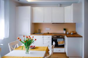 eine Küche mit weißen Schränken und einem Tisch mit einer Blumenvase in der Unterkunft Cozy apartment in the downtown in Győr