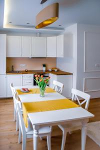 eine weiße Küche mit einem gelben Tisch und weißen Stühlen in der Unterkunft Cozy apartment in the downtown in Győr