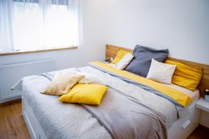 ein Bett mit gelben und blauen Kissen darauf in der Unterkunft Cozy apartment in the downtown in Győr