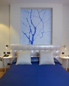a bedroom with a blue bed with two white pillows at Hotel Campoamor in Oviedo