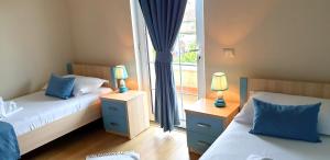 a bedroom with two beds with blue pillows and a window at Open Doors Bed & Breakfast in Shkodër