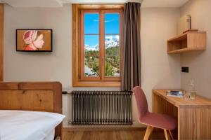 a bedroom with a window and a desk and a chair at Hotel Nest- und Bietschhorn in Blatten im Lötschental