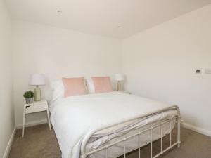 a bedroom with a white bed with pink pillows at The Beach Halt in Perranporth