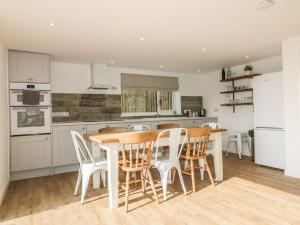 a kitchen with a wooden table and white chairs at The Beach Halt in Perranporth