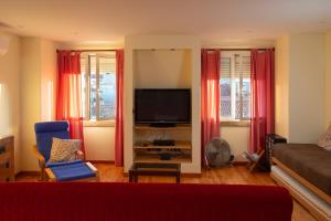ein Wohnzimmer mit einem TV und roten Vorhängen in der Unterkunft Home in Lisbon Duplex in Lissabon