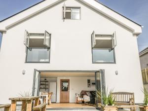 a white house with large windows and a patio at The Beach Halt in Perranporth