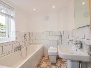 a white bathroom with a tub and a toilet and a sink at The Beach Halt in Perranporth +32 photos