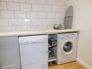 a kitchen with a washer and dryer under a counter at The Beach Halt in Perranporth