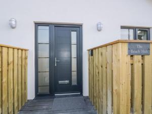 a black door on a white building with a wooden fence at The Beach Halt in Perranporth
