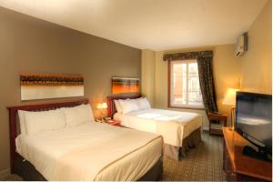 a hotel room with two beds and a flat screen tv at Place Saint Bernard Mont Tremblant in Mont-Tremblant