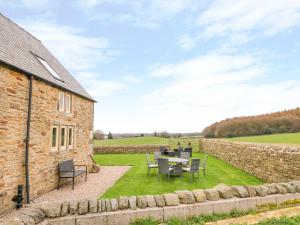 a patio with a table and chairs next to a stone building at Woodthorpe Cruck Cottage in Chesterfield