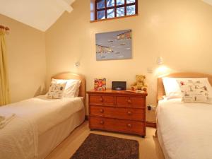a bedroom with two beds and a teddy bear on a dresser at Barras Cottage in Dwyran