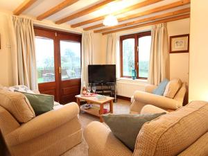 a living room with two couches and a tv at Barras Cottage in Dwyran
