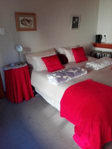 a bedroom with two beds with red and white pillows at The Olde House in Port Elizabeth