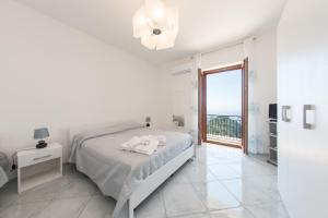 a white bedroom with a bed and a balcony at Lo Smeraldo Luxury Home Ravello by ElodeaGroup in Scala