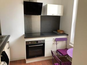 La Villa B في شوليه: مطبخ صغير مع موقد ومقعد أرجواني