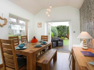 comedor con mesa de madera y sillas en Bay View - Benllech en Benllech