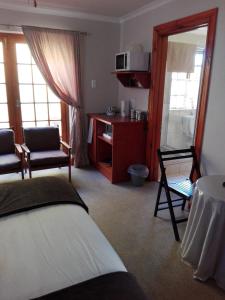Habitación de hotel con cama, mesa y sillas en The Olde House, en Port Elizabeth