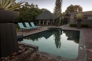 a swimming pool with chairs and a gazebo at Klip en Kristal Guest House in Bela-Bela
