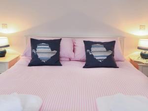 a bed with pink and white striped sheets and pillows at Bron Haul in Llanfairpwllgwyngyll