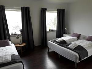 two beds in a room with two windows at Guesthouse Geldingaholt in Árnes