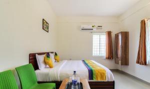 a bedroom with a bed and two green chairs at Itsy By Treebo - Riyas Grand in Tirupati