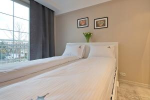 duże białe łóżko w pokoju z oknem w obiekcie Imperial Apartments - Baltica w mieście Sopot