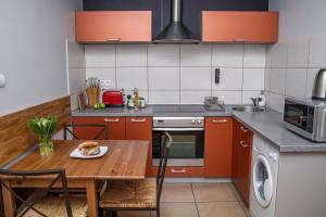 eine Küche mit orangefarbenen Schränken und einem Holztisch in der Unterkunft Red Kurka Apartments in Krakau