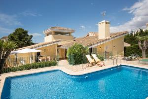 a villa with a swimming pool in front of a house at Villa Olympus. Piscina Privada. La Manga Club in Atamaría