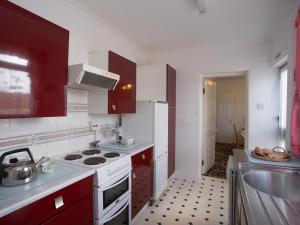 een keuken met rode kasten en een witte kookplaat bij Bro Dawel in Beaumaris
