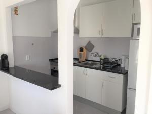 a kitchen with white cabinets and a white refrigerator at Caparica Sol in Costa da Caparica