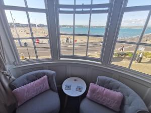 a room with two chairs and a view of a beach at Seacrest Guest House in Weymouth