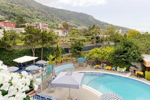 una piscina al aire libre con sombrillas, mesas y sillas en Hotel Carmencita, en Anacapri
