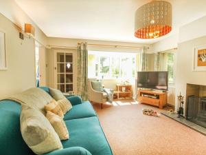 a living room with a blue couch and a television at Bryn Ffynnon in Benllech