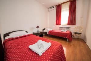 a bedroom with two beds with red sheets and a window at Lafodija in Međugorje