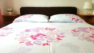 a bed with pink butterflies on a white comforter at The Orange One in Novigrad Istria