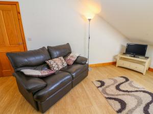 a leather couch in a living room with a television at Shorefields Two in Morecambe