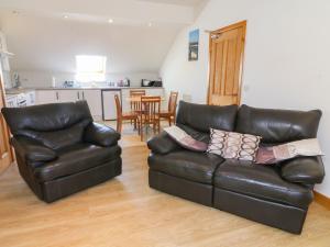 a living room with a leather couch and chairs at Shorefields Two in Morecambe