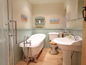 ein Badezimmer mit zwei Waschbecken und einer Badewanne und einer Toilette in der Unterkunft Cae'r Dyni Caer Dyni in Criccieth + 16 Fotos